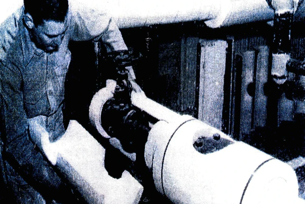Worker installing asbestos pipe insulation